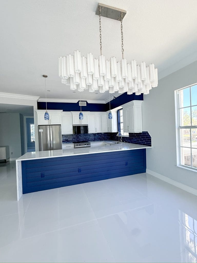 Luxury coastal kitchen with a navy island and pendant lighting by Premier Magnolia Homes