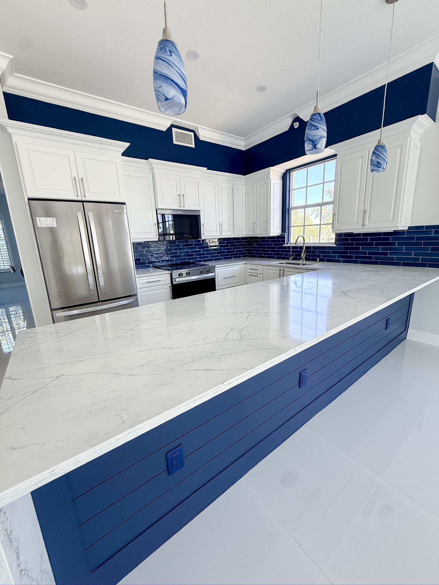 Renovated kitchen with white perimeter cabinetry and a navy island