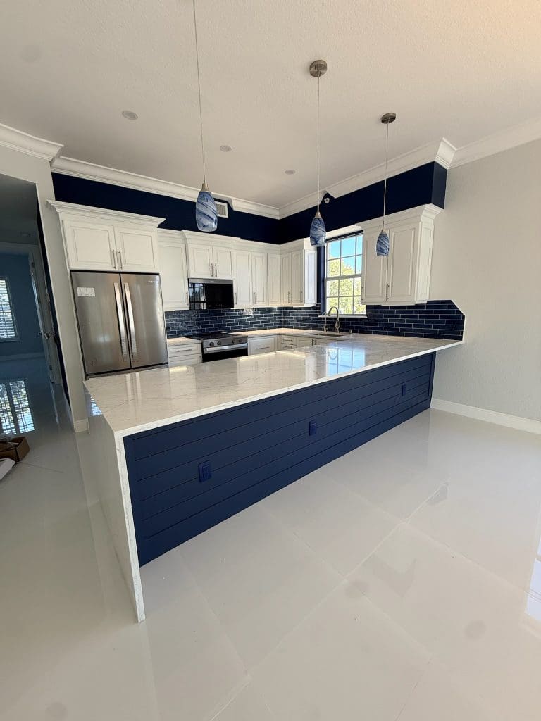 Kitchen with a navy island, quartz top and pendant lighting