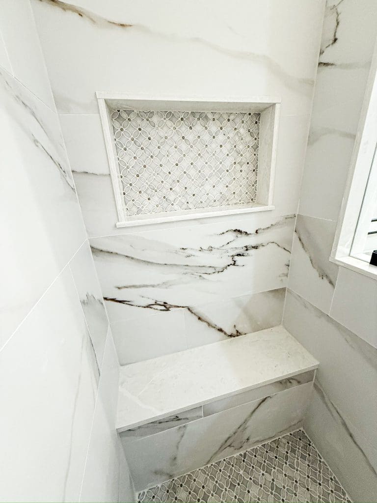 Marble walk-in shower with a built-in bench by Premier Magnolia Homes