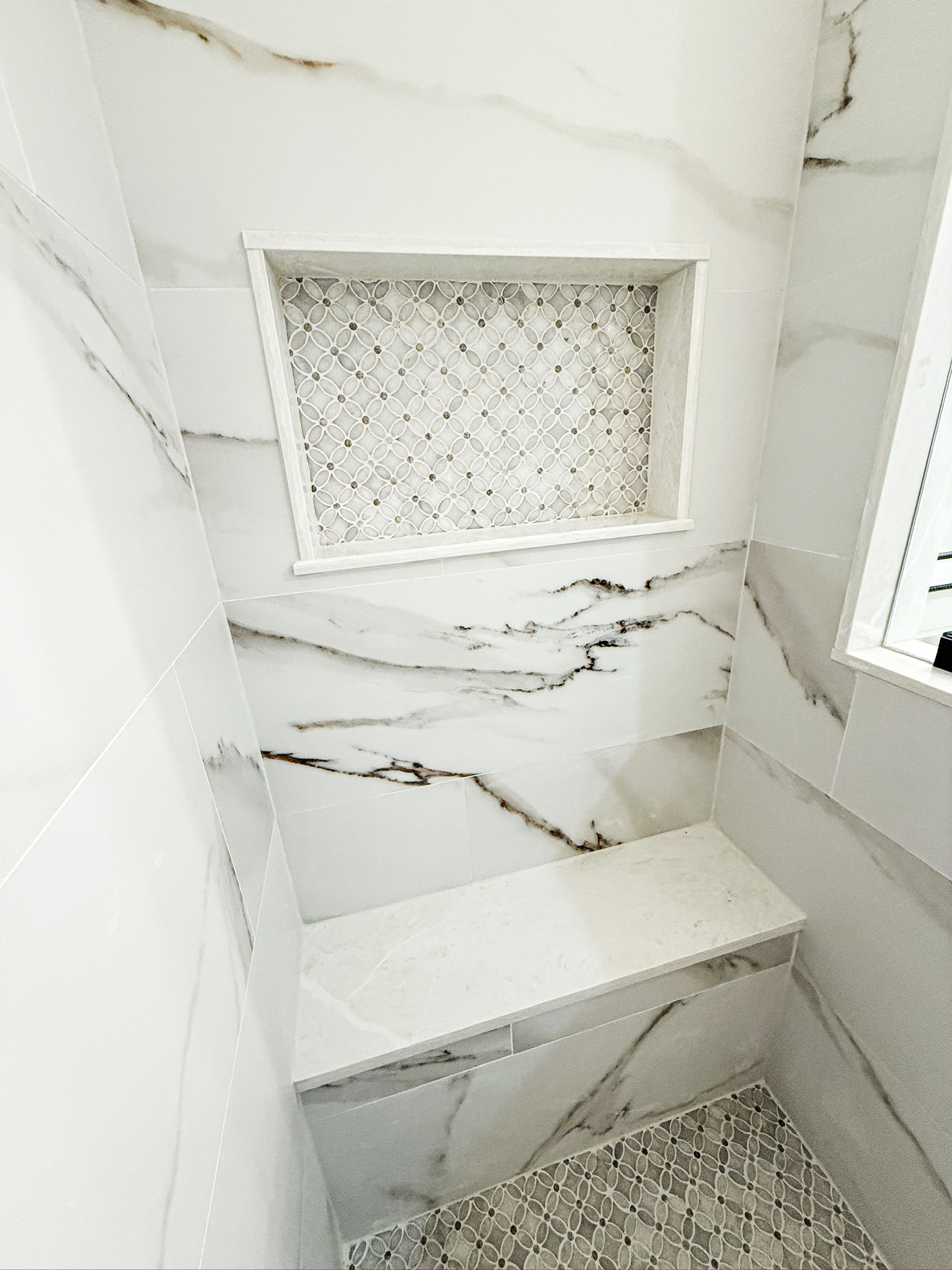 Marble walk-in shower with a built-in bench by Premier Magnolia Homes