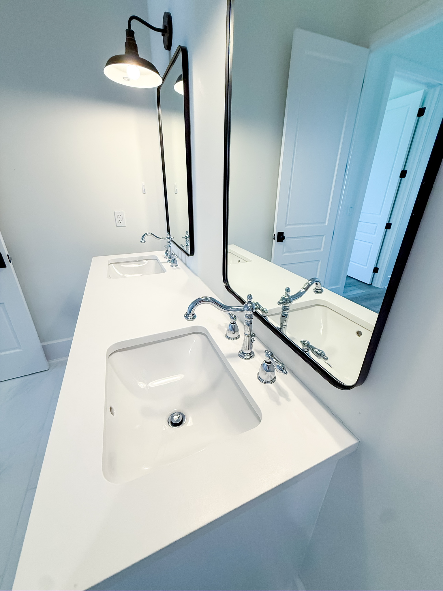 Bathroom vanity with a modern black mirror and wall sconce