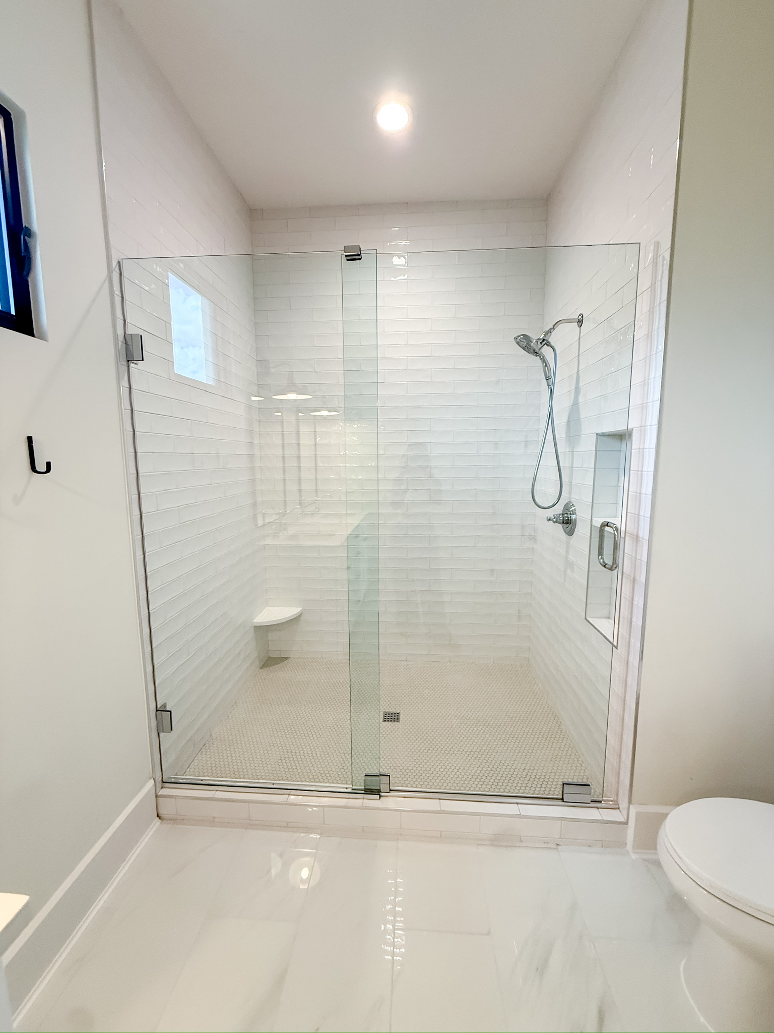 Walk-in shower with frameless glass and tile carried to the ceiling