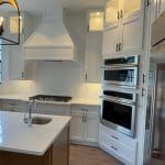 Remodeled estate kitchen with custom hood and wall ovens in a North Naples golf community home