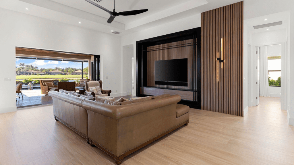 Living room with a walnut slat media wall opening to the water through full-height glass